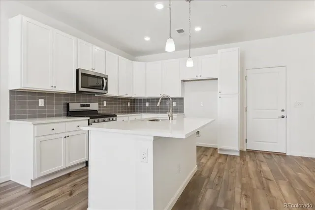 a kitchen with kitchen island a sink stainless steel appliances and white cabinets