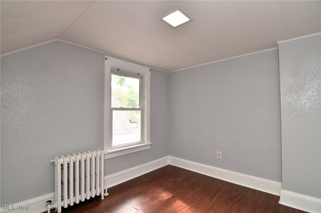 1683 Sunview Road Cleveland, OH 44124 - Photo 28 of 35 Spare room with ornamental molding, lofted ceiling, dark hardwood / wood-style flooring, and radiator heating unit