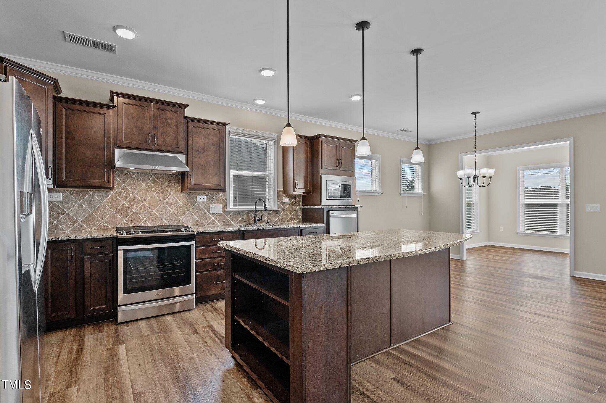 1013 Calista Drive Wake Forest, NC 27587 - Photo 15 of 40 a kitchen with stainless steel appliances granite countertop a sink a stove and a wooden floors