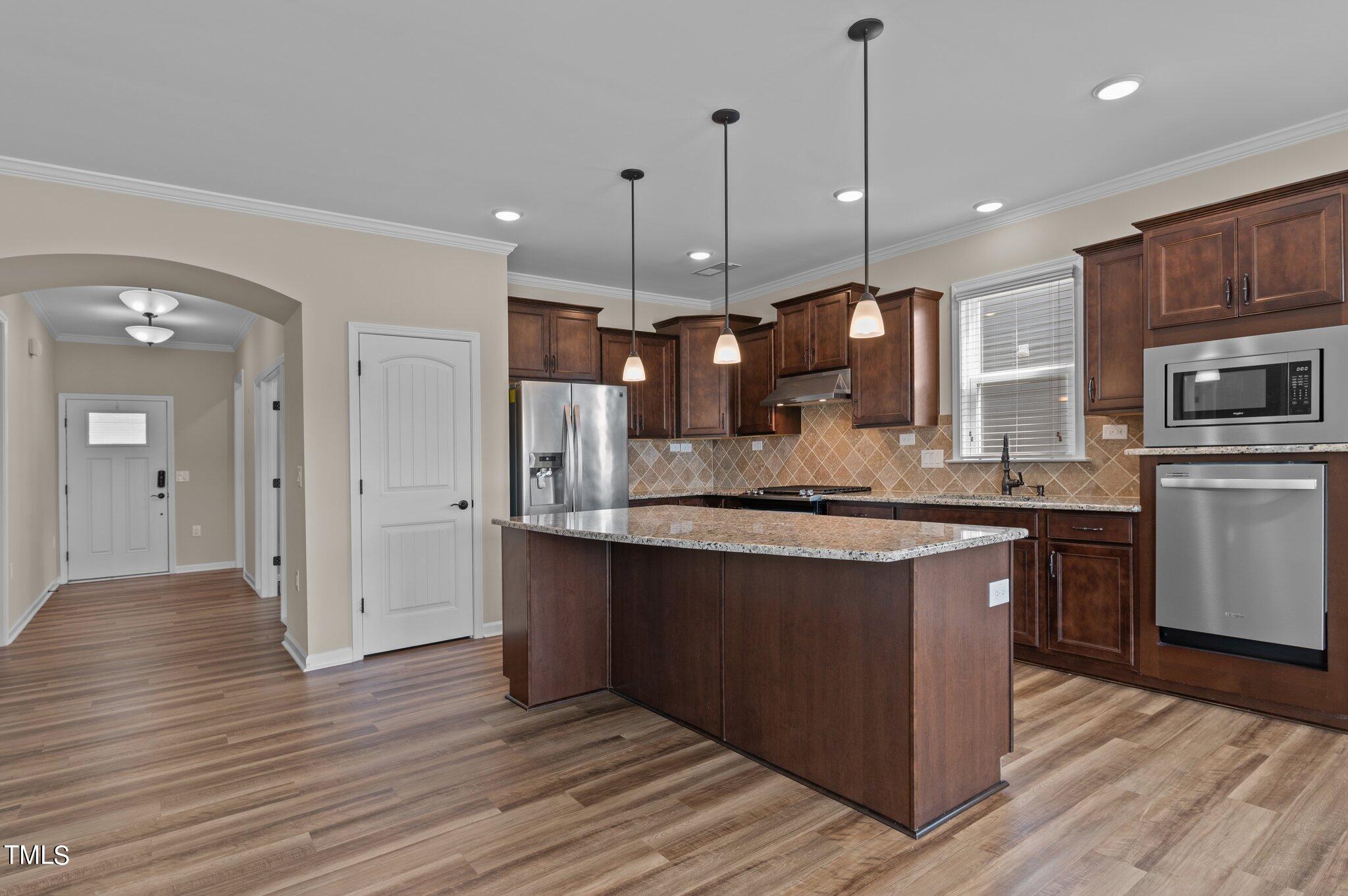 1013 Calista Drive Wake Forest, NC 27587 - Photo 17 of 40 a large kitchen with stainless steel appliances granite countertop a refrigerator a oven a large island with wooden cabinets and floor