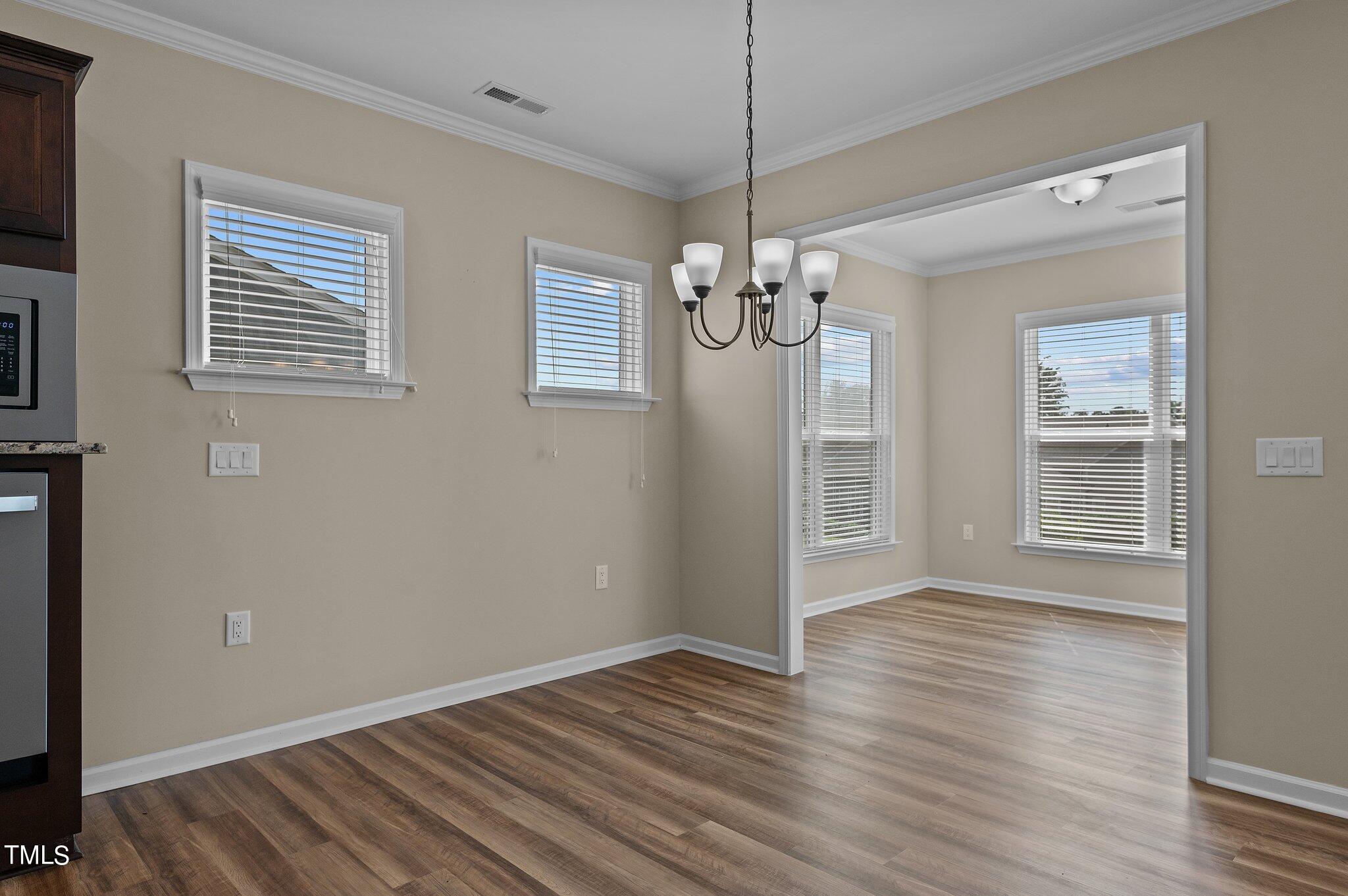 1013 Calista Drive Wake Forest, NC 27587 - Photo 19 of 40 an empty room with wooden floor a chandelier and windows