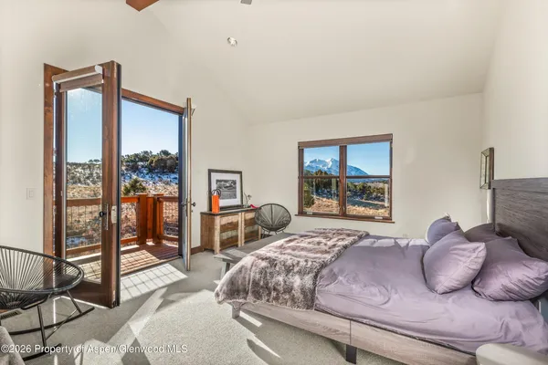 a bedroom with a bed and large windows