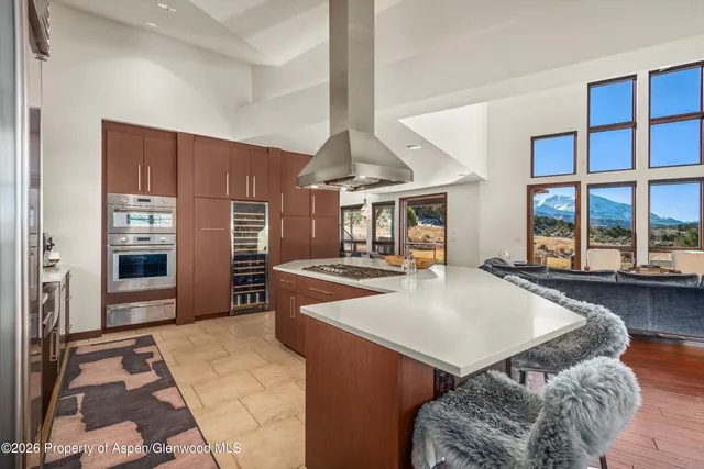 a living room with furniture a large window and stainless steel appliances