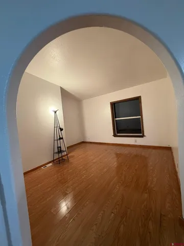 a view of an empty room with wooden floor and a window