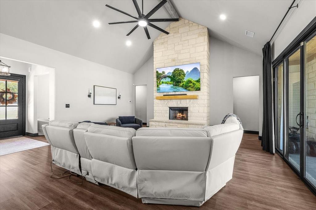 6080 Cates Rnch Drive Godley, TX 76044 - Photo 9 of 40 Vaulted ceilings, wood-finish flooring, stone-clad fireplace with wood mantel, contemporary ceiling fan, and sliding glass doors