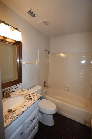 a bathroom with a granite countertop sink toilet a large mirror and bathtub