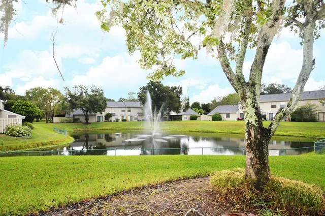 a view of a lake with a yard and large trees