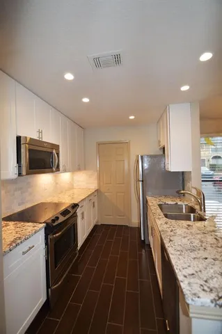 a kitchen with stainless steel appliances granite countertop a stove a sink and a microwave