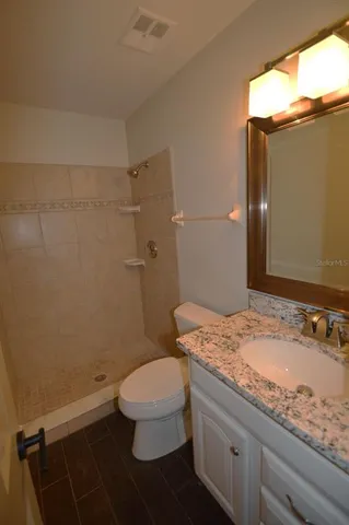 a bathroom with a granite countertop sink toilet and shower