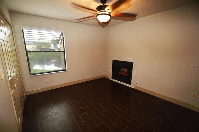 an empty room with wooden floor fan and windows