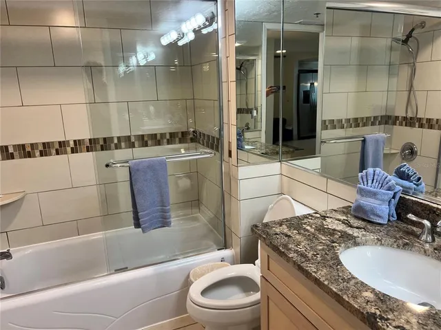 a bathroom with a granite countertop sink a toilet and shower