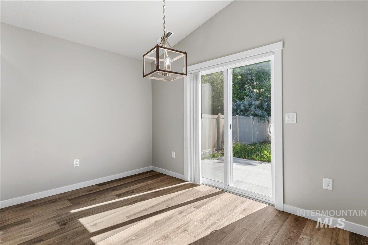 3091 S Green Boise, ID 83709 - Photo 9 of 27 Bright interior space featuring a sliding glass door, a contemporary geometric chandelier, wood-finish flooring, and light-toned wall finishes