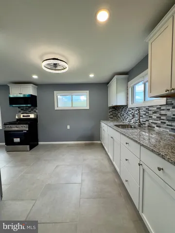 a kitchen with granite countertop a stove a sink and a refrigerator