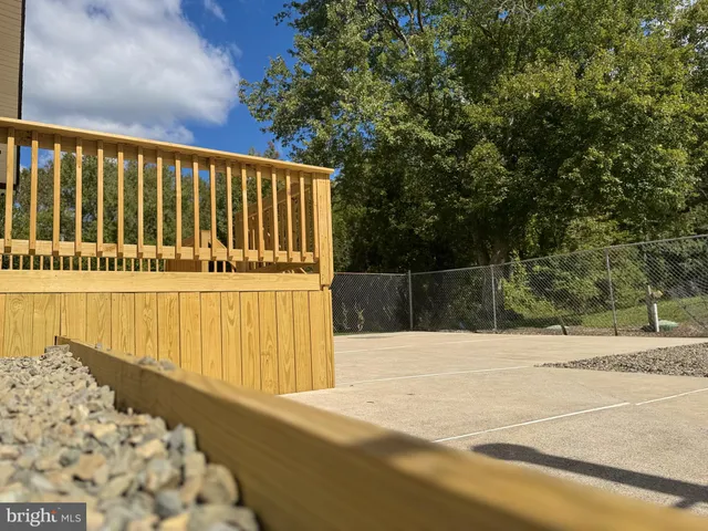 a house that is sitting in the grass with large trees and sky view