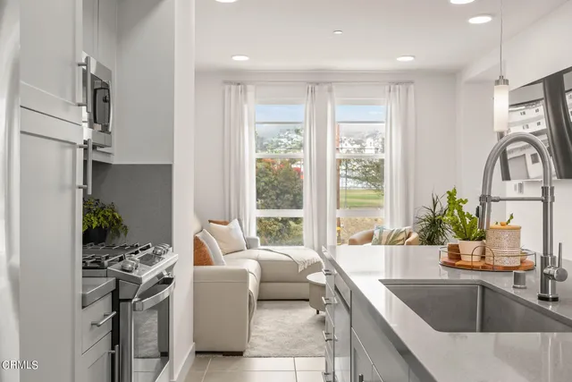 a large white kitchen with a large window and stainless steel appliances