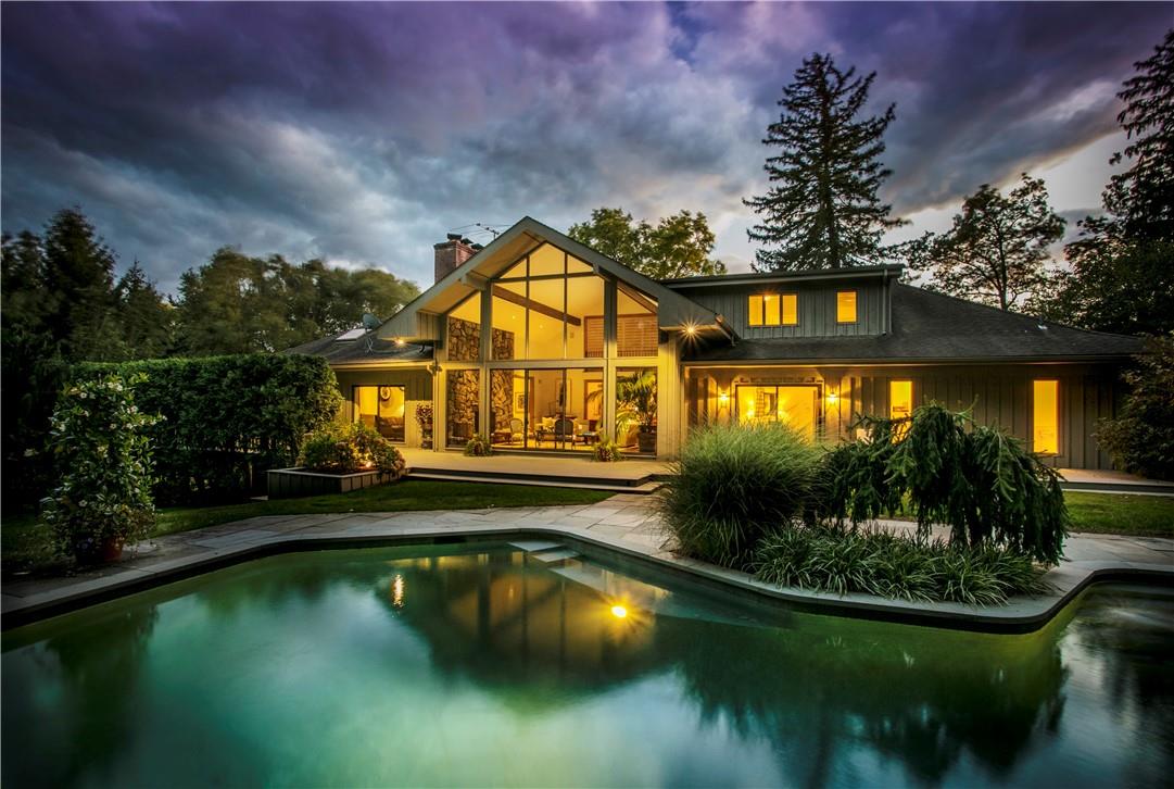 Dramatic twilight pic highlighting pool, lush landscaping and open concept living