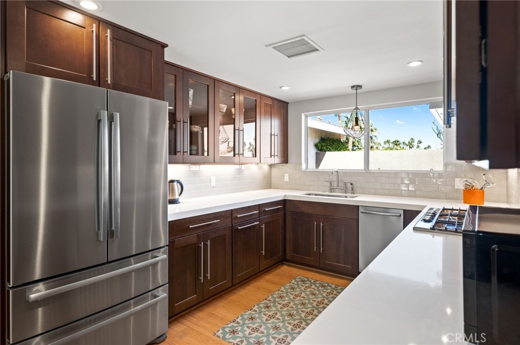 72543 Beavertail Street Palm Desert, CA 92260 - Photo 15 of 45 a kitchen with stainless steel appliances granite countertop a refrigerator a sink dishwasher a stove and white countertops with wooden floor