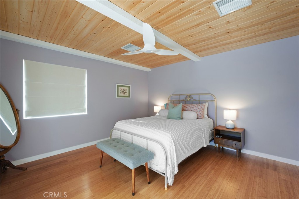 72543 Beavertail Street Palm Desert, CA 92260 - Photo 26 of 45 a bedroom with a bed a mirror and wooden floor