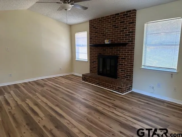 a view of an empty room with a fireplace and a window