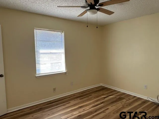 an empty room with a window and ceiling fan