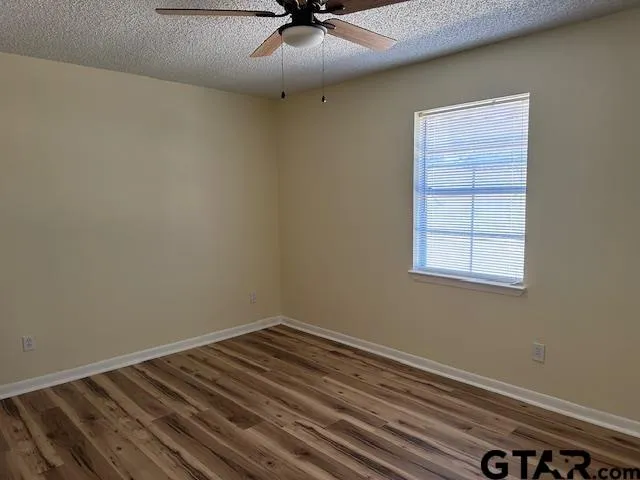 an empty room with a window and a ceiling fan
