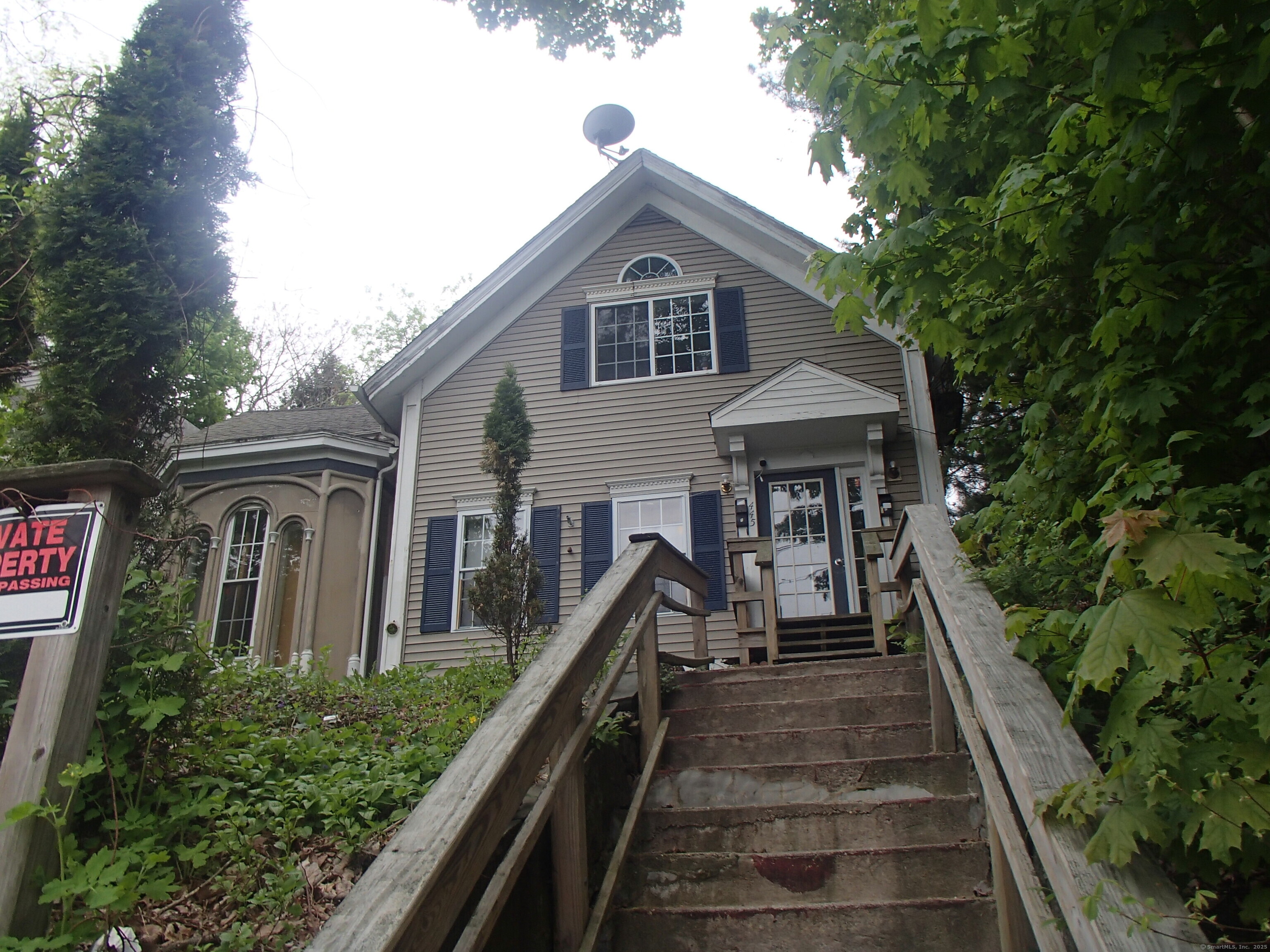 a front view of house along with deck and trees