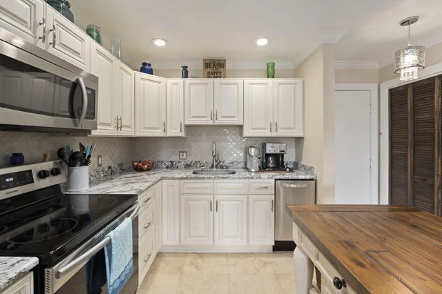 a kitchen with kitchen island white cabinets and stainless steel appliances