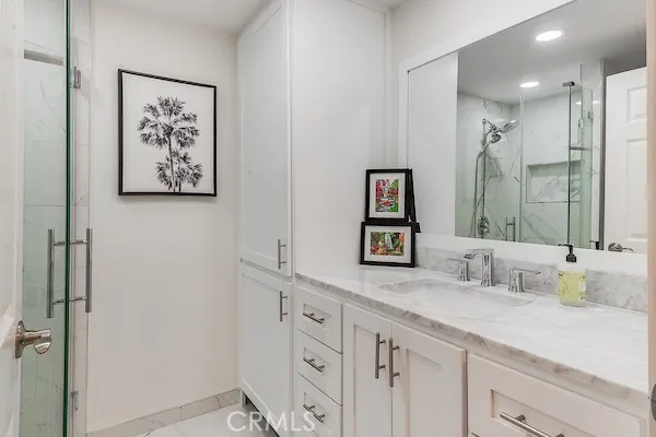 a bathroom with a granite countertop sink a mirror and a shower