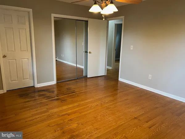 an empty room with wooden floor and chandelier fan