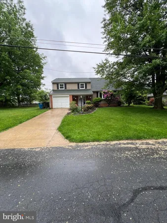 a view of a house with a yard and large tree