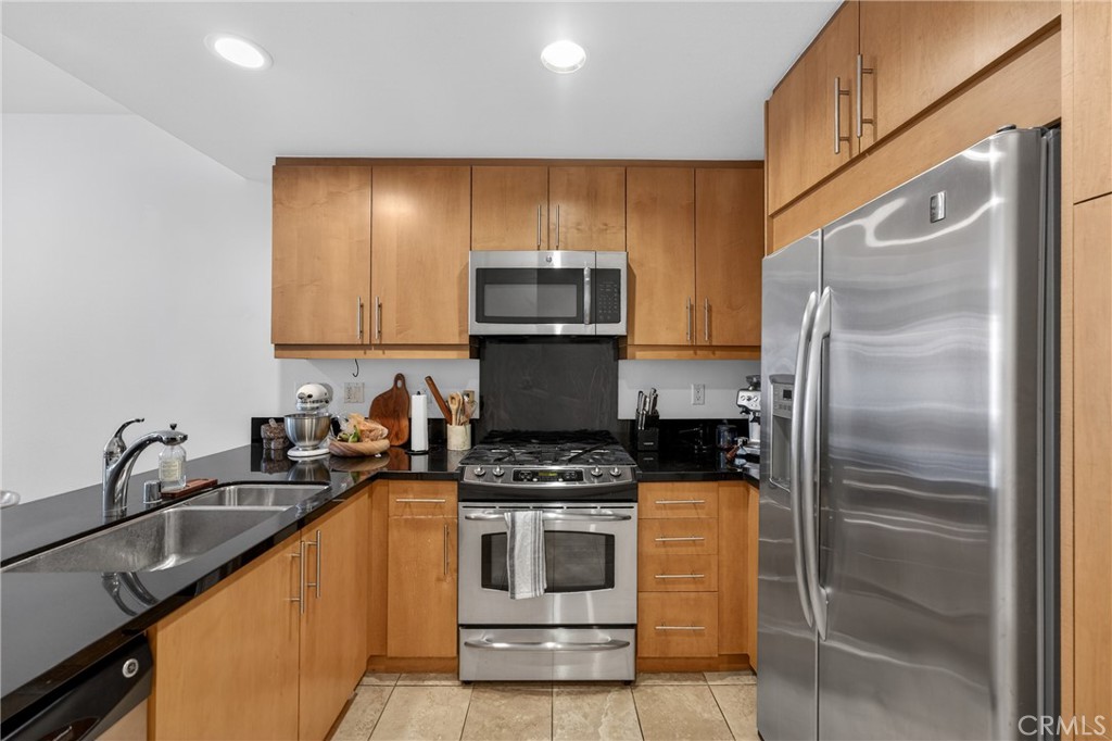 150 The Promenade North, Unit 415 Long Beach, CA 90802 - Photo 16 of 46 a kitchen with granite countertop a refrigerator and a stove top oven