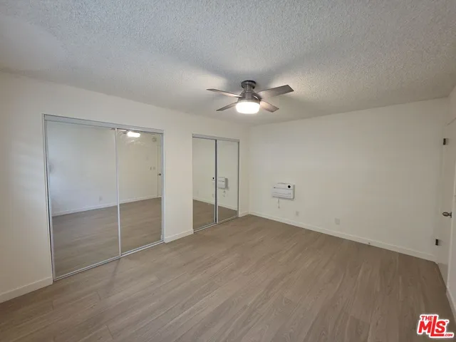 wooden floor in an empty room with a chandelier fan