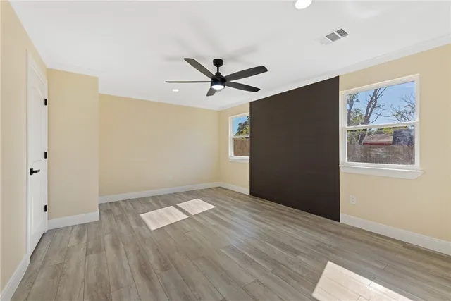 an empty room with wooden floor and a ceiling fan