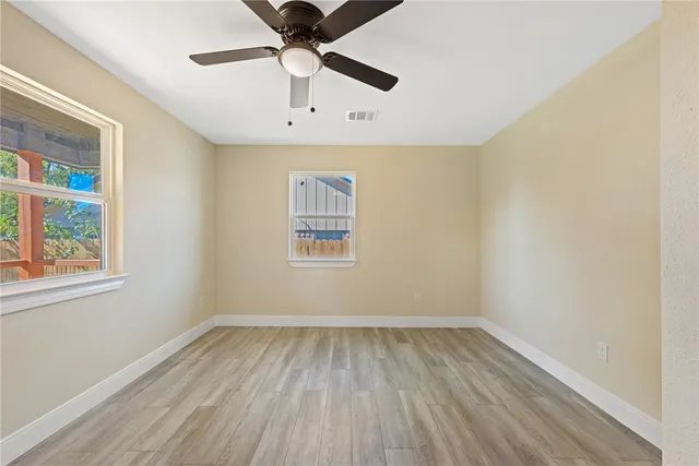 an empty room with a window and ceiling fan