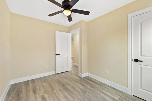 an empty room with wooden floor and ceiling fan