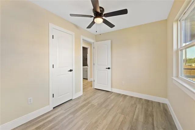 a view of empty room with wooden floor and fan