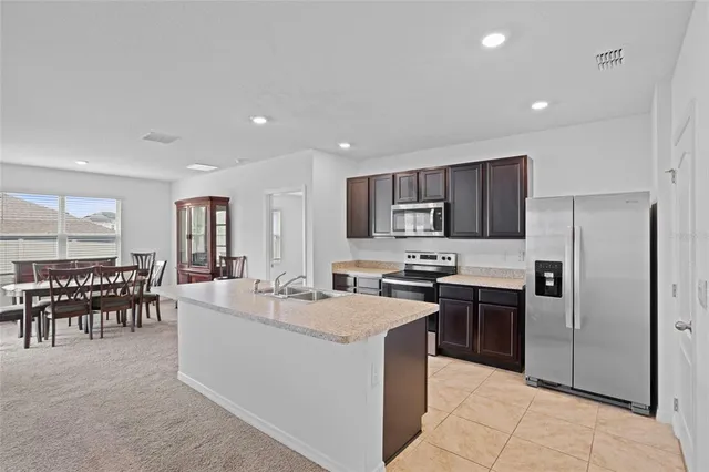 a large kitchen with kitchen island a sink a counter top stainless steel appliances and cabinets