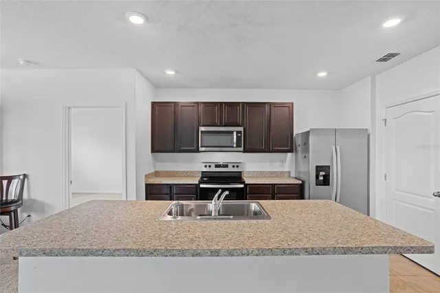 a kitchen with granite countertop a refrigerator and a stove top oven