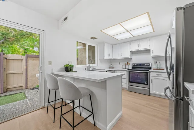 a kitchen with a refrigerator a stove a sink and a dining table with wooden floor