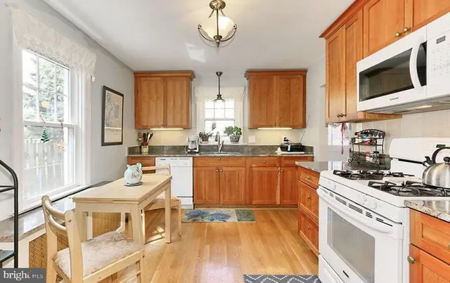 a kitchen with stainless steel appliances granite countertop a stove a sink dishwasher and white cabinets with wooden floor