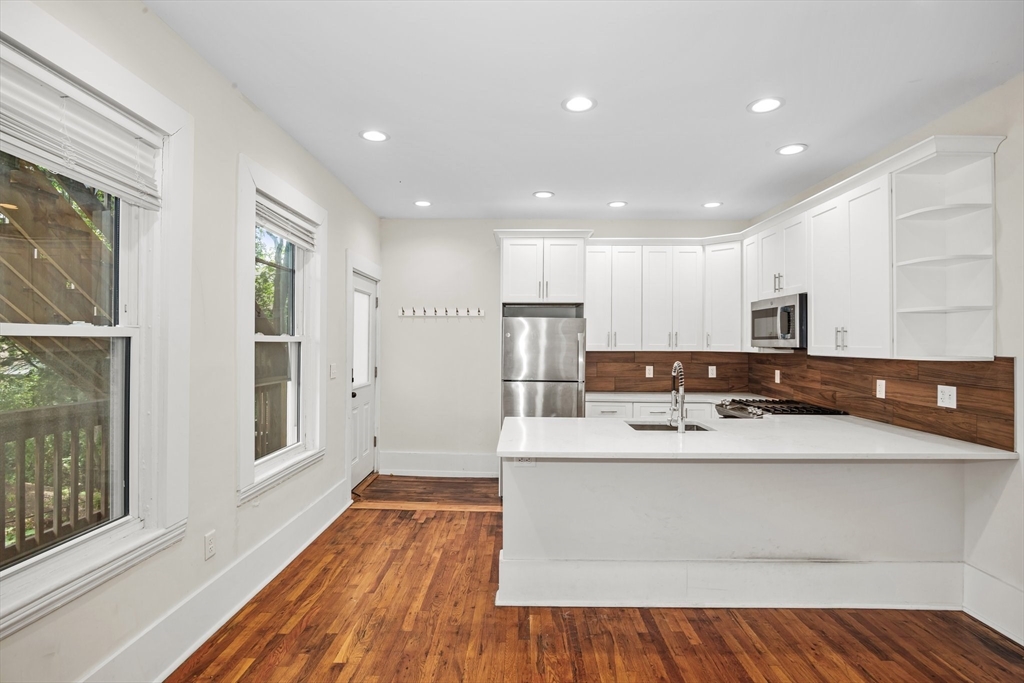 35 Oak Avenue Worcester, MA 01605 - Photo 8 of 34 a large white kitchen with wooden floors and stainless steel appliances