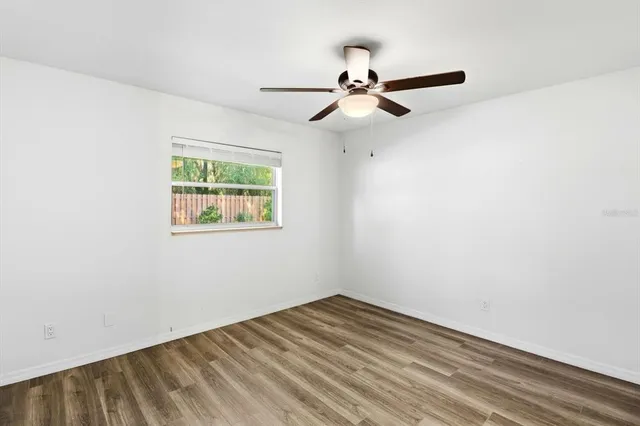 an empty room with a window and a ceiling fan