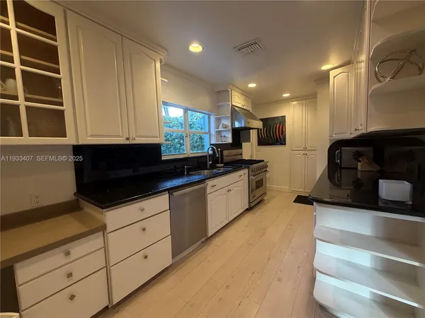 a kitchen with granite countertop white cabinets and stainless steel appliances