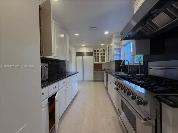 a kitchen with stainless steel appliances a sink a stove top oven a counter space and cabinets