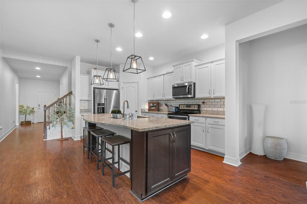 4730 111th Terrace East Parrish, FL 34219 - Photo 13 of 60 a kitchen with stainless steel appliances granite countertop a table chairs stove and microwave