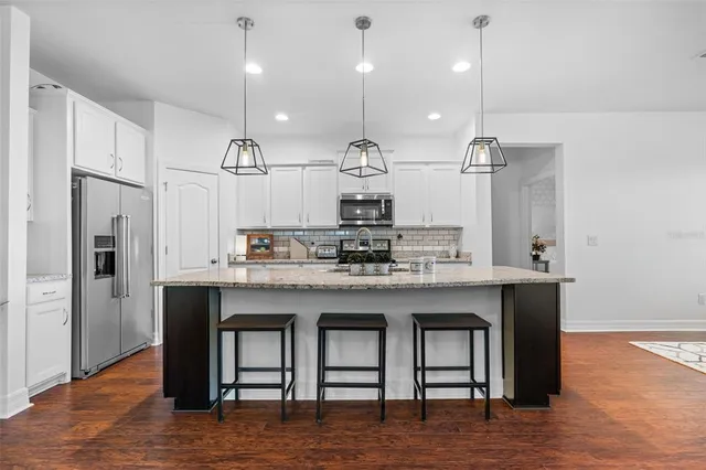 a kitchen with stainless steel appliances granite countertop a sink a refrigerator and a stove