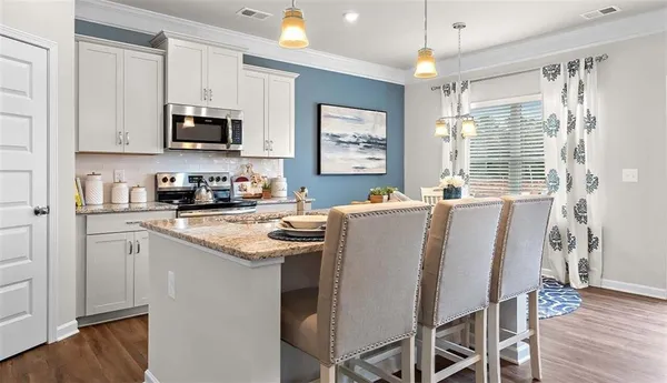 a kitchen with stainless steel appliances granite countertop a stove a sink dishwasher a microwave oven a refrigerator with white cabinets and wooden floor