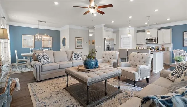 a living room with furniture kitchen view and a chandelier