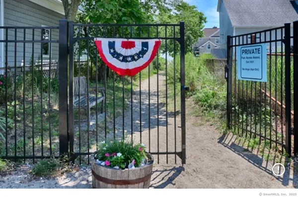 a view of a sign board with a small yard and potted plants