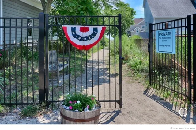 a view of a sign board with a small yard and potted plants